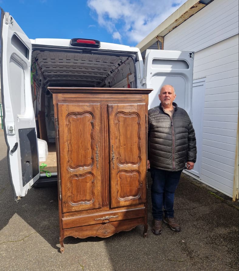 Michael Munoz, brocanteur dans le Sud-Ouest, devant une armoire ancienne